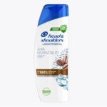 Flacon de shampoing Head & Shoulders Anti-Haarverlust avec bouchon bleu. L'étiquette indique le nom du produit, ses bienfaits et une image de grains de café et de gouttes d'eau. Le texte est principalement en allemand. Dakar