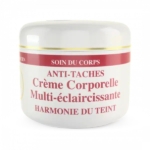 Un pot blanc de crème de soin portant l'inscription « Anti-Taches Crème Corporelle Multi-éclaircissante Harmonie du Teint » avec une bande rouge et or sur le dessus. Le texte est en français, indiquant qu'il s'agit d'une crème pour le corps harmonisant le teint. Dakar
