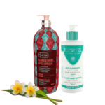 Deux flacons : le gel douche doux Phit 26, orné d'un motif rouge, et la lotion clarifiante Topsgel, blanche avec des touches de vert. Un petit bouquet de frangipanier blanc et jaune est posé devant. Dakar