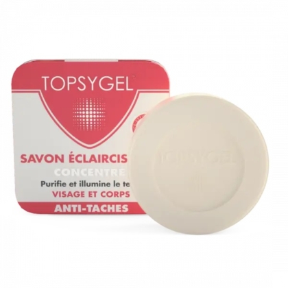 Barre de savon ronde beige devant une boîte rectangulaire rouge et blanche avec un dessin et un texte, incluant les mots « Topsygel » et « Savon Éclaircissant ». Dakar