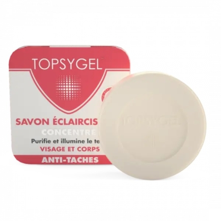 Barre de savon ronde beige devant une boîte rectangulaire rouge et blanche avec un dessin et un texte, incluant les mots « Topsygel » et « Savon Éclaircissant ». Dakar