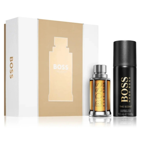 Coffret cadeau Hugo Boss comprenant un flacon d'eau de toilette Boss The Scent et un déodorant en spray cylindrique. L'emballage est blanc avec des touches dorées, affichant le nom de la marque et la silhouette du flacon de parfum. Dakar