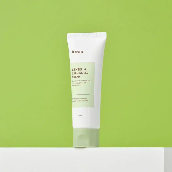 Un tube de gel-crème apaisant à la centella d'iUNIK se détache sur un fond vert vif. Le tube blanc porte une étiquette verte et un bouchon gris. L'étiquette mentionne un effet éclaircissant et un effet antirides. Dakar