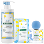 Trois produits Klorane bébé : un flacon de lotion hydratante avec pompe, une boîte de savon doux et un pot d'eau de toilette en verre avec un bouchon sphérique bleu. Tous arborent des motifs floraux ludiques bleus et jaunes sur fond blanc. Dakar