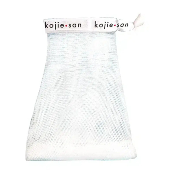Pochette à savon en filet blanc avec fermeture à cordon sur le dessus. La bande supérieure est ornée de l'inscription « kojie.san » en lettres noires et rouges. La pochette présente une surface texturée, conçue pour contenir le savon et faire mousser. Dakar