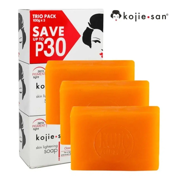 Image d'un trio de savons Kojie San. L'emballage affiche « ÉCONOMISEZ JUSQU'À 30 P » et un visage stylisé. Trois savons orange sont présentés devant la boîte, chacun imprimé du logo Kojie San. Dakar