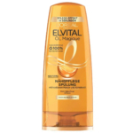 Un flacon orange de l'après-shampoing Elvital Öl Magique de L'Oréal Paris pour cheveux secs, aux huiles de marula et de camélia. Il revendique un effet soin immédiat et est fabriqué à partir de plastique 100 % recyclé. Texte en allemand. Dakar