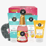 Un coffret cadeau dans une boîte rose contenant cinq produits : un gel douche, une crème pour les mains, un lait corporel, une eau de toilette vanille-framboise et un chouchou noir. Tous les articles sont étiquetés « Les Petits Plaisirs » avec des motifs floraux. Dakar