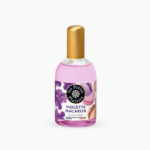 Un flacon en verre transparent de l'Eau de Toilette Violette Macaron « Les Petits Plaisirs » avec un bouchon doré. L'étiquette est ornée de fleurs violettes et de macarons, et le parfum à l'intérieur est rose clair. Dakar