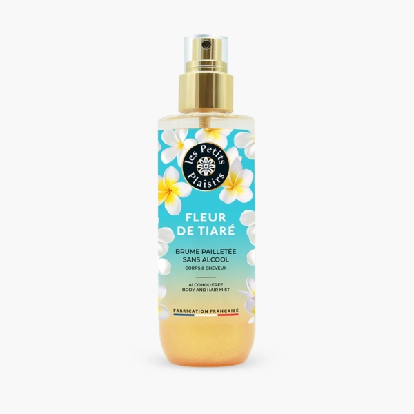 Un flacon spray de 200 ml de "Les Petits Plaisirs Brume Pailletée Fleur de Tiaré" présente un design tropical avec des fleurs blanches et jaunes, étiqueté comme une brume corps et cheveux sans alcool, fabriquée en France. Dakar