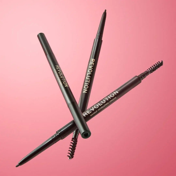 Trois crayons à sourcils noirs, portant l'inscription « REVOLUTION » imprimée en doré, sont croisés sur un fond rose. Chaque crayon est doté d'une brosse goupillon à une extrémité et d'une pointe rétractable à l'autre. Dakar