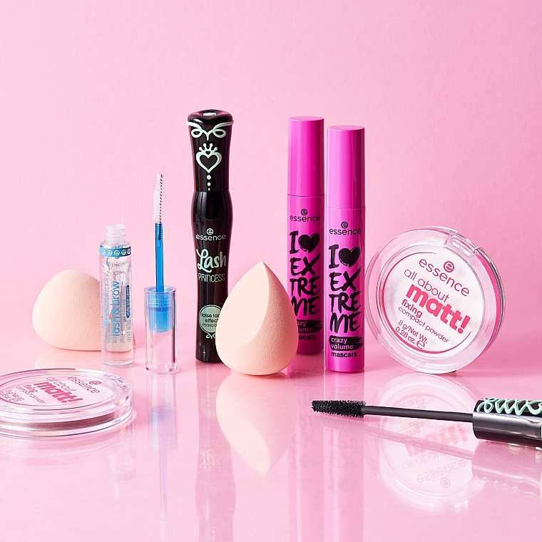 Une collection de produits de maquillage Essence disposés sur une surface rose. Elle comprend des mascaras, un correcteur de couleur, deux éponges à maquillage et des poudres compactes. L'emballage est coloré avec des touches de noir, de rose et de bleu. Dakar