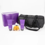 Un ensemble de produits Mauiboussin comprenant une boîte violette, un sac de sport noir, deux tubes violets et un flacon de parfum en forme de pyramide rempli de liquide ambré, le tout disposé sur un fond blanc. Dakar