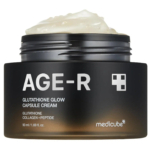 Un pot de crème gélule Medicube AGE-R Glutathione Glow, avec un contenant noir et un couvercle blanc. La crème, à la texture onctueuse, est visible au-dessus du bord. L'étiquette met en valeur des ingrédients comme le glutathion, le collagène et les peptides. Format : 50 ml. Dakar