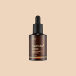 Flacon compte-gouttes en verre de sérum éclat au glutathion Medicube avec une étiquette marron foncé et un bouchon noir sur fond beige. Dakar