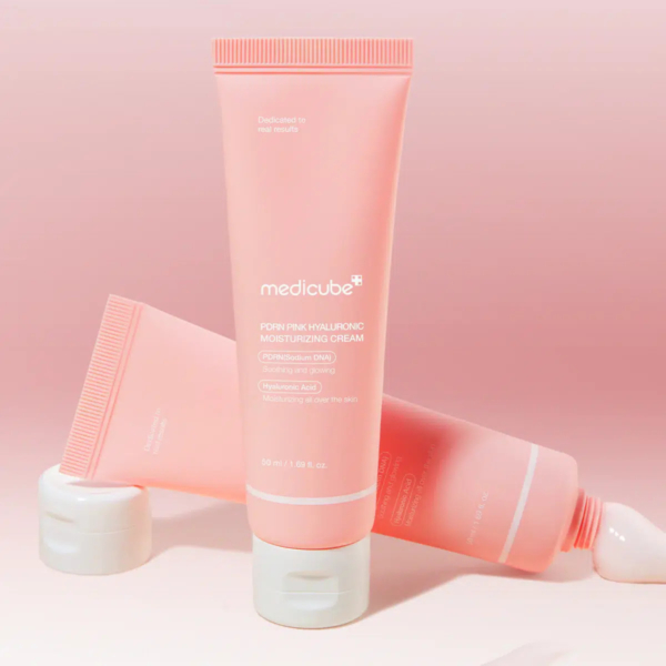 Deux tubes de crème hydratante hyaluronique Medicube Pore Pink sont présentés. L'un est vertical, l'autre incliné, sur fond dégradé rose. L'emballage met en avant les bienfaits de l'hydratation et de la douceur de la peau. Dakar