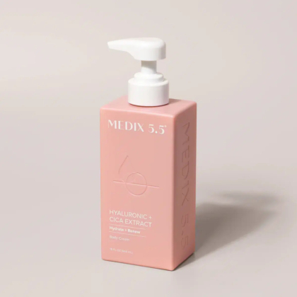 Un flacon carré rose de crème pour le corps Medix 5.5 avec une pompe blanche. L'étiquette indique « Hyaluronique + Extrait de Cica » et « Hydratation + Régénération ». Le fond est gris clair uni. Dakar
