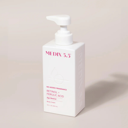 Un flacon pompe rectangulaire blanc portant l'inscription « MEDIX 5.5 » avec les mentions « Rétinol + Acide férulique » et « Crème pour le corps Age Rewind ». Le flacon est rose et sans parfum ajouté. Il contient 444 ml (15 oz liq.) de produit. Dakar