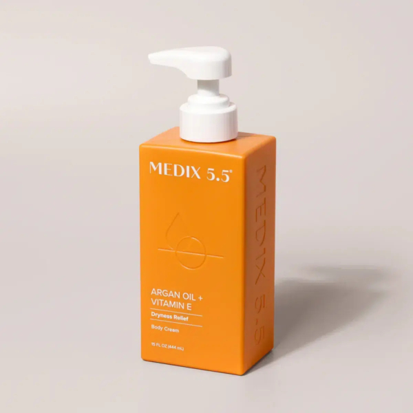 Flacon pompe orange de crème pour le corps Medix 5.5 à l'huile d'argan et à la vitamine E, étiqueté pour le soulagement de la sécheresse, sur fond clair. Dakar