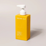 Flacon pompe rectangulaire jaune étiqueté « Crème Corps Éclat et Raffermissante Medix 5.5 Vitamine C + Curcuma ». Le flacon est doté d'un bouchon pompe beige et repose sur une surface grise. Dakar