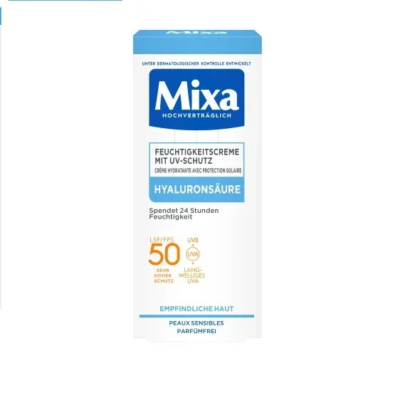 Coffret pour la crème hydratante Mixa avec protection UV. L'emballage est blanc avec des touches et un texte bleus. Ses principales caractéristiques incluent l'acide hyaluronique, un SPF 50, une protection UVA/UVB et une compatibilité avec les peaux sensibles. L'étiquette est en allemand. Dakar