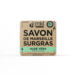 Une boîte carrée beige de savon de Marseille Surgras à l'aloe vera, conçu pour le corps et les mains. L'emballage arbore la marque « mkl green nature » et met en avant « 98 % d'origine naturelle » et « Fabriqué en France ». Dakar