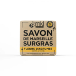 Un pain de savon carré MKL Green Nature, étiqueté « Savon de Marseille Surgras » et « Fleurs d'Agrumes », pour le corps et les mains. Son emballage beige avec inscription noire et jaune indique qu'il est d'origine naturelle à 98 % et fabriqué en France. Dakar