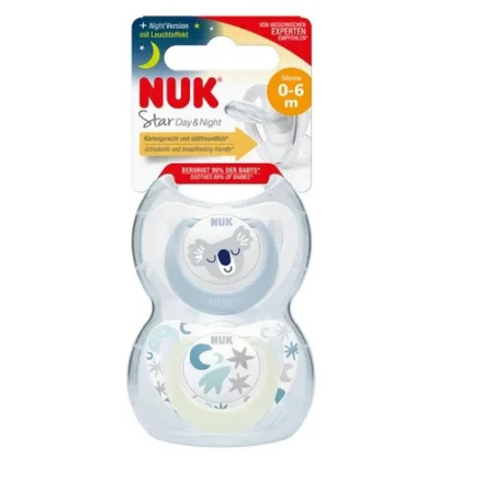 Coffret contenant deux sucettes NUK pour bébés de 0 à 6 mois. L'une présente un motif nuage endormi, l'autre un motif étoiles et nuages. L'emballage met en valeur la version nuit grâce à une fonction phosphorescente. Dakar