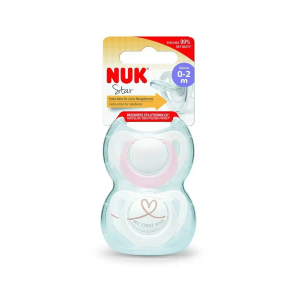 Un emballage contenant une sucette NUK Star en silicone pour les bébés de 0 à 2 mois. L'emballage est principalement blanc avec des touches de jaune et de rouge. La sucette est visible, ornée d'un cœur et de l'inscription « Ma première NUK ». Dakar