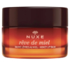 Un pot de baume à lèvres au miel Rêve de Miel de Nuxe Paris avec un couvercle marron foncé. Le contenant en verre présente une couleur ambrée dégradée et un texte blanc. Dakar