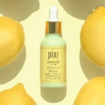 Un flacon compte-gouttes de sérum à la vitamine C Pixi est centré sur un fond jaune clair, entouré de citrons entiers. L'étiquette du flacon le décrit comme un concentré éclaircissant. Dakar