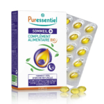 Présentation de l'emballage du complément alimentaire Puressentiel Sommeil+. La boîte est blanche avec des touches de violet et de vert, ornée d'un motif de gouttes d'huile. À côté se trouvent un blister et des capsules jaunes. Contient 30 capsules. Dakar