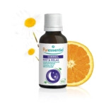 Un flacon d'huiles essentielles Puressentiel Repos & Relax est placé devant une fleur de camomille et une tranche d'orange. L'étiquette arbore un motif de croissant de lune et d'étoiles. Dakar