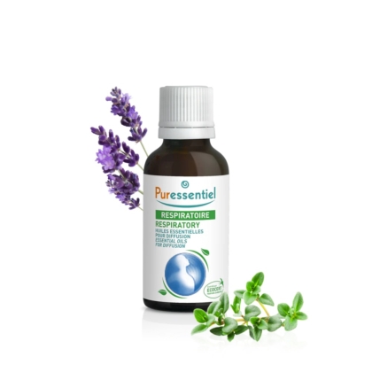 Un flacon d'huiles essentielles Puressentiel Respiratoire, coiffé d'un bouchon argenté. Autour du flacon, des brins de lavande et des herbes vertes, probablement du thym, sur fond blanc. Dakar