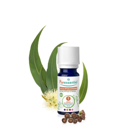 Un flacon d'huile essentielle d'Eucalyptus Citriodora Puressentiel est exposé, entouré de feuilles, de fleurs et de gousses d'eucalyptus. L'étiquette est principalement blanche et verte, avec un cercle rouge et des touches de bleu. Le bouchon est blanc. Dakar