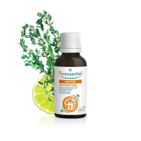 Un flacon d'huiles essentielles Puressentiel Air Pur avec un bouchon blanc. L'étiquette arbore des tons orange et bleu sarcelle. Derrière, une tranche de citron vert éclatant et un brin d'herbes fraîches. Le produit porte le logo Ecocert. Dakar