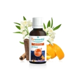 Un flacon d'huile essentielle Puressentiel étiqueté « Cocooning » est entouré de bâtons de cannelle, d'écorces d'orange et de fleurs blanches aux feuilles vertes. Le flacon représente une cabane douillette dans un paysage enneigé. Dakar