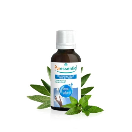 Un flacon d'huiles essentielles Puressentiel pour diffusion est entouré de feuilles vertes fraîches. L'étiquette présente des éléments bleus et blancs, avec du texte en français et en anglais. Dakar
