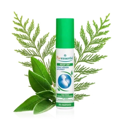 Un flacon de Puressentiel Resp OK Air Spray au bouchon vert est présenté devant des feuilles de fougère et de sauge vertes. L'étiquette arbore un symbole circulaire bleu, et le texte mentionne son utilisation pour purifier l'air et soulager les sensibilités saisonnières. Dakar