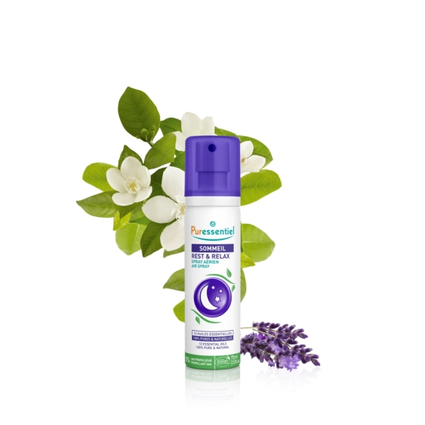 Un vaporisateur étiqueté « Puressentiel Repos & Détente » se dresse devant une branche feuillue verte et des fleurs blanches, avec un brin de lavande violette à sa base. Le flacon est orné de touches de violet et d'un motif en croissant de lune. Dakar