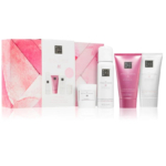 Un coffret cadeau de soins pour la peau, présenté dans un coffret rose et blanc au design géométrique, contenant trois produits : un gel douche moussant, une crème pour le corps et un gommage. Chaque produit est présenté dans un contenant rose et blanc. Dakar