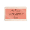 Pain de savon au beurre de karité SheaMoisture à la noix de coco et à l'hibiscus pour peaux ternes, 227 g. L'étiquette est rose avec un texte foncé détaillant des ingrédients comme le champignon Songyi. Le savon présente une texture légèrement blanc cassé. Dakar