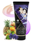 Un tube de crème de massage Shunga au parfum de fruits exotiques est présenté debout. L'emballage présente une représentation artistique de deux personnages enlacés. À côté du tube sont illustrés des fruits exotiques comme l'ananas, les agrumes, le raisin et le kiwi. Dakar