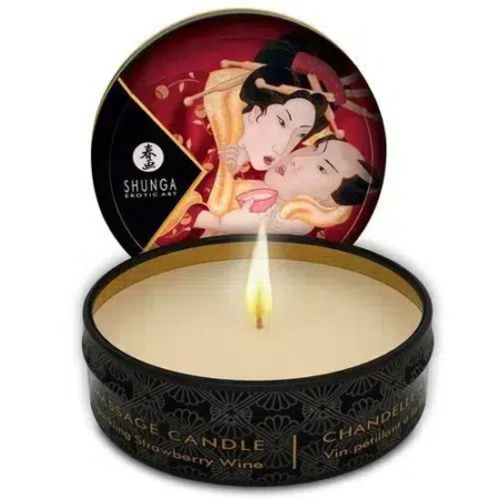 Une bougie allumée dans une boîte noire aux motifs complexes. Le couvercle est ouvert, laissant apparaître une œuvre d'art représentant un couple. L'étiquette indique « Shunga Erotic Art » et « Strawberry Wine Massage Candle ». Dakar