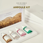 Image d'un kit d'ampoules Skin1004 avec quatre flacons compte-gouttes soigneusement disposés dans une boîte. Chaque flacon contient un liquide de couleur différente : marron, transparent, rose et vert. La boîte présente une image d'un paysage de montagne pittoresque et présente un design minimaliste. Dakar