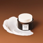 Un pot de PHA Resurfacing Centella, une crème hydratante de nuit, est posé sur une surface marron. La crème est partiellement étalée autour du pot, mettant en valeur sa texture. Le pot est doté d'une étiquette et d'un couvercle blancs. Dakar