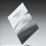 Un masque en tissu flottant SKIN1004 à la Centella de Madagascar sur fond dégradé. Son design minimaliste présente des images en niveaux de gris d'un paysage montagneux. Dakar
