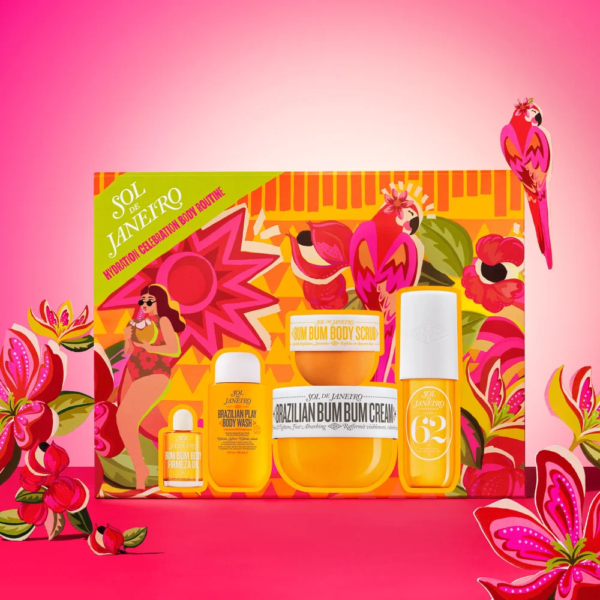 Un coffret cadeau coloré composé de produits de soins corporels Sol de Janeiro sur fond de fleurs roses et orange éclatantes et d'oiseaux tropicaux. Ce coffret comprend une crème pour le corps, un gommage, un spray corporel et un gel douche. Dakar