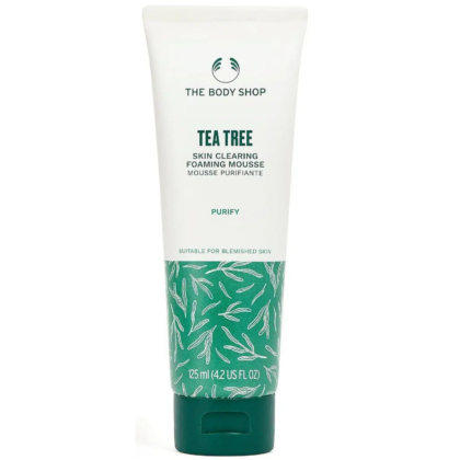 Un tube de mousse purifiante à l'arbre à thé The Body Shop. Ce tube blanc au bouchon vert est conçu pour purifier la peau et convient aux peaux à imperfections. Il contient 125 ml (4,2 fl oz US) et arbore un motif de feuilles sur le fond. Dakar