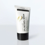 Tube blanc de sérum au rétinol 1,0 % The Inkey List Supersolutions avec bouchon noir. Le texte sur le tube souligne son utilisation pour les cicatrices, les marques et les rides. Une noisette de crème est visible sur le tube. Dakar